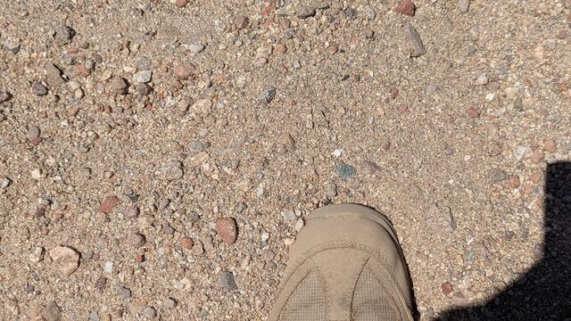 A photo of sediment in a wadi in California with a boot for scale