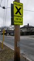 two traffic signs complimented by give way road markings. the first sign is large and florescent, saying, "stop for pedestrians," and the second sign is small and white, reading "caution: vehicles not required to stop."