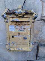 Vielle boîte aux lettres de couleur jaune, accrochée sur un mur