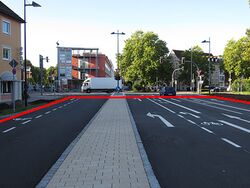 Germany: lanes=5 lanes:forward=3 lanes:backward=1 lanes:both_ways=1 turn:lanes:both_ways=left surface:both_ways=paving_stones (Include the center lane in the overall lane count.)